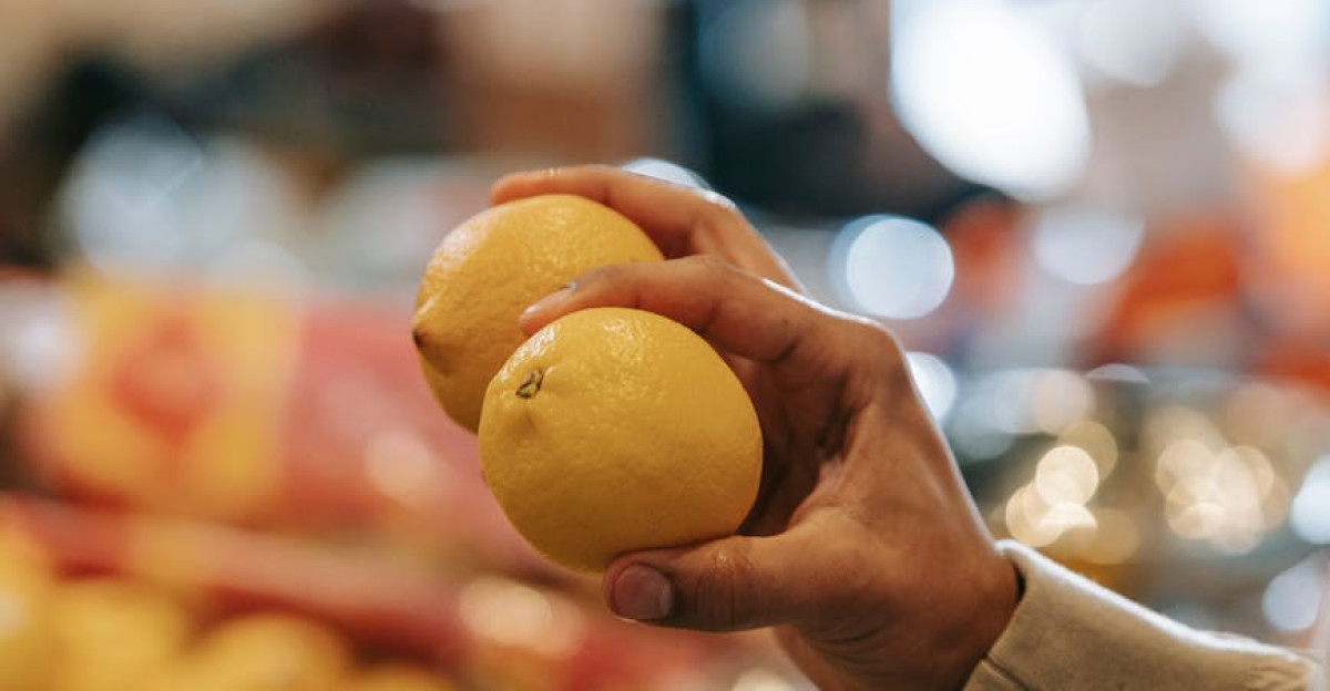 A close-up shot of a man selecting ripe lemons in a grocery store with blurred background