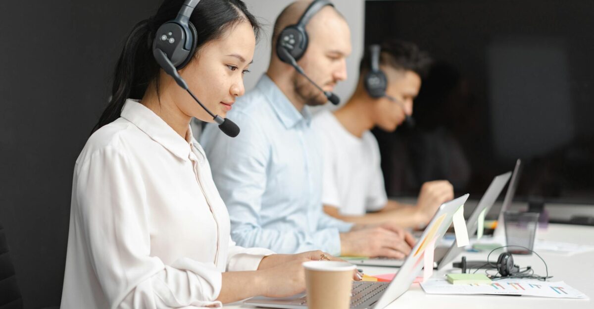 Customer service agents efficiently handle calls using laptops and headsets in a modern office