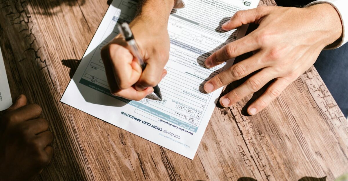 Hands writing on a consumer loan credit application form on a wooden table