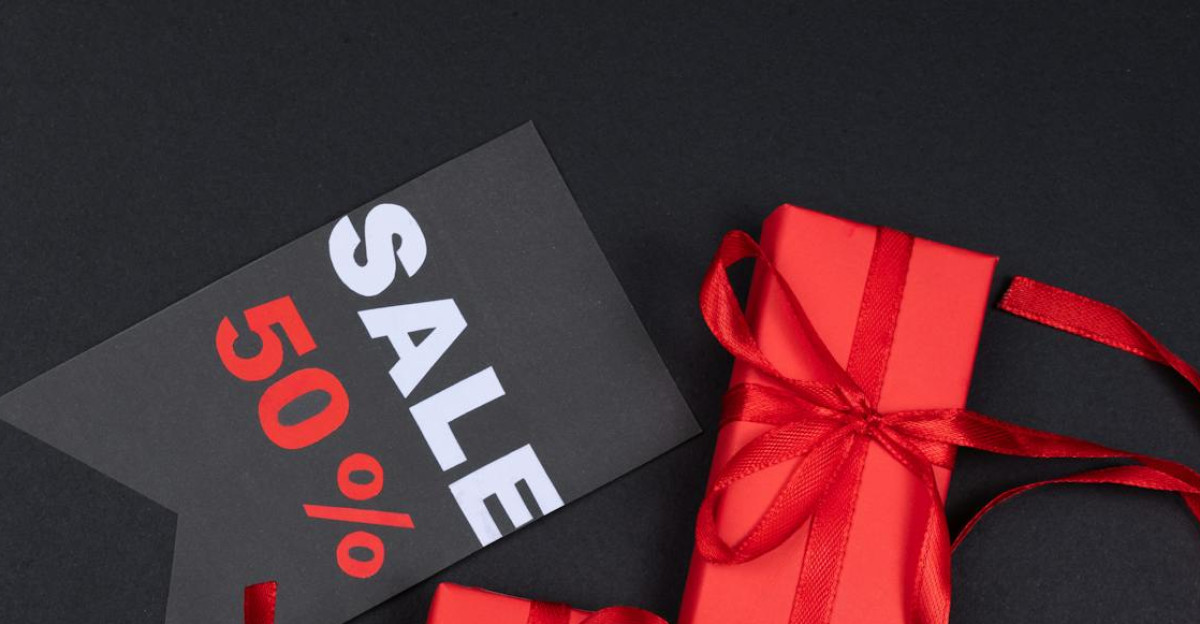 Red gift boxes with ribbons and 50 sale tag against black background