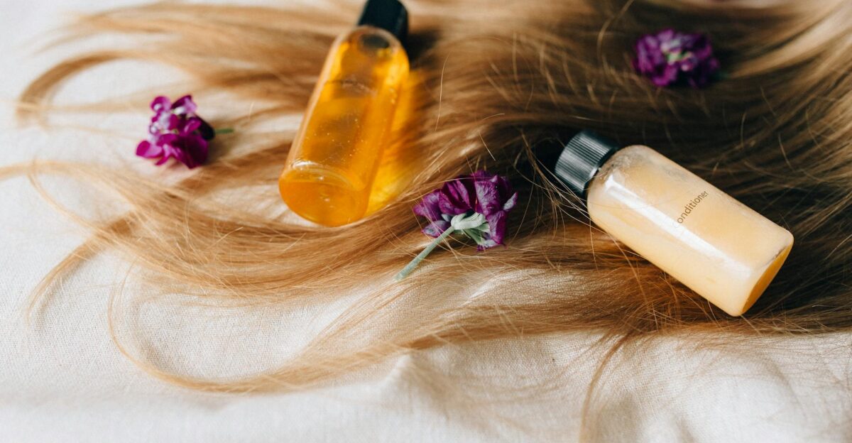 Hair care products on a bed of hair and flowers symbolizing luxury and beauty