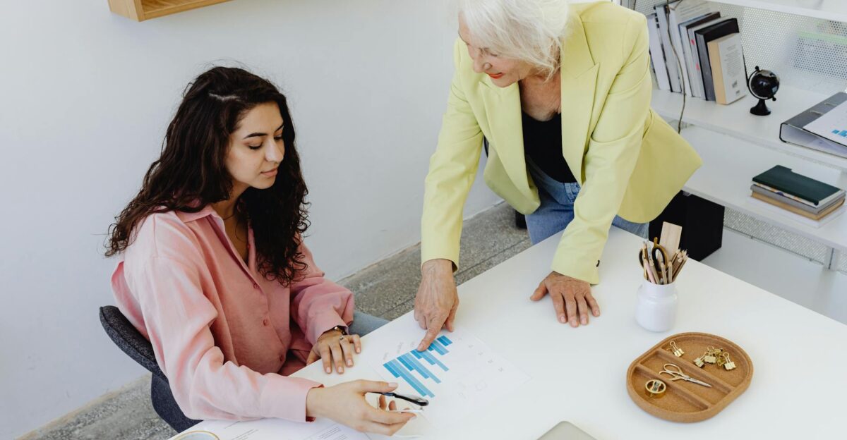 Two women analyzing business data in a modern office setting focusing on teamwork