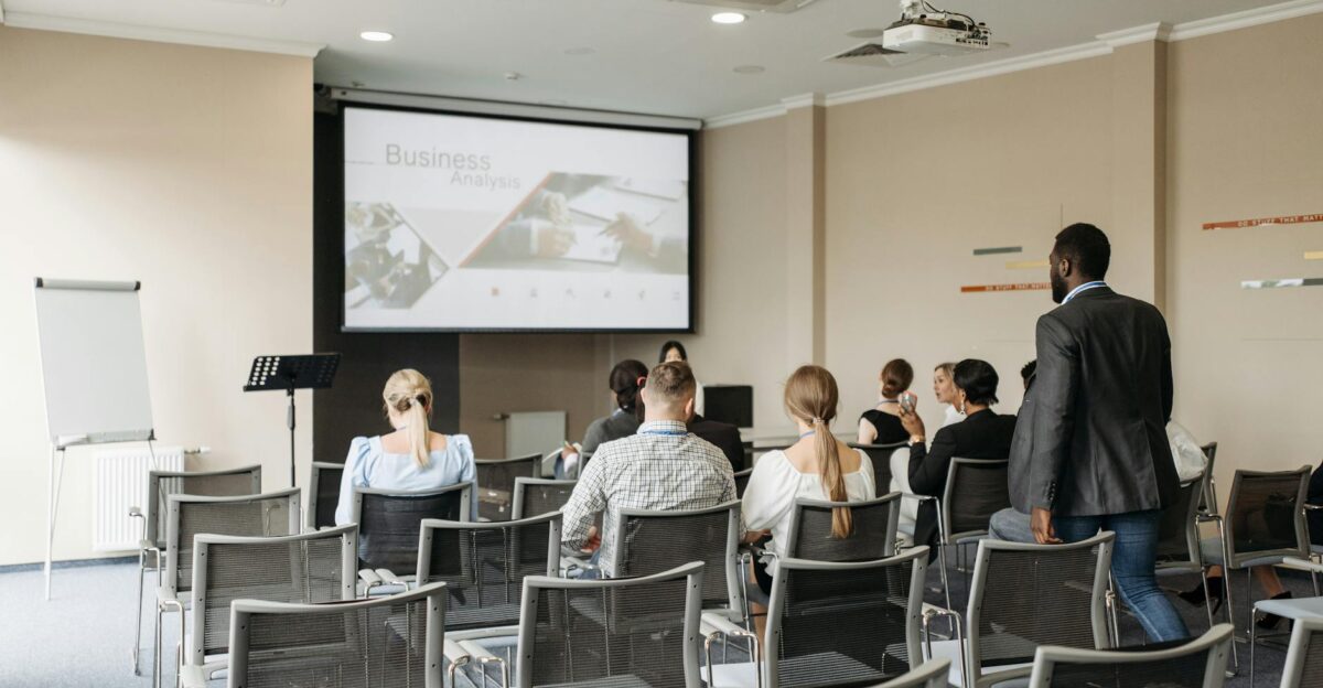 Business conference attendees listening to a presentation in an office setting