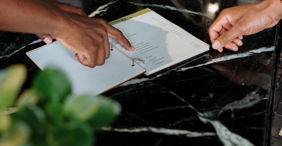 Hands pointing at menu on black marble counter inside a shop