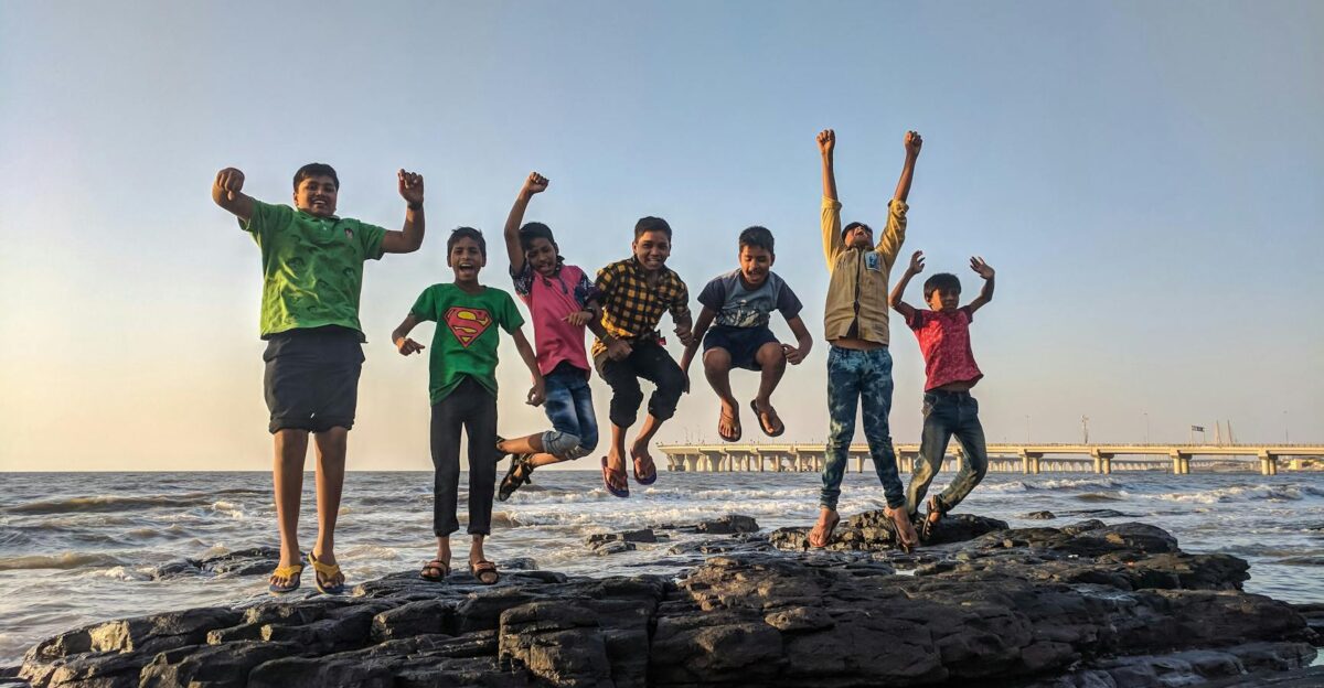 Group of kids joyfully jumping on rocks by the seaside Fun and playful moment captured outdoors