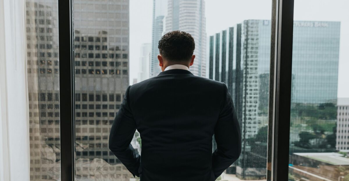 man putting hands on pocket while standing in front of glass wall