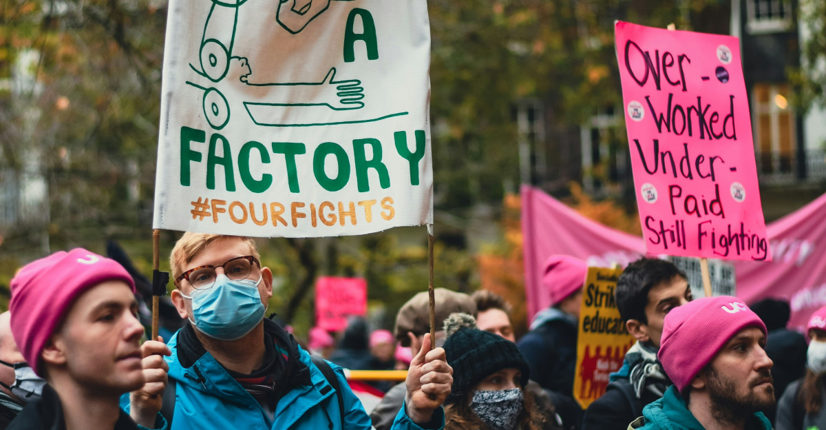 a group of people holding signs and wearing masks