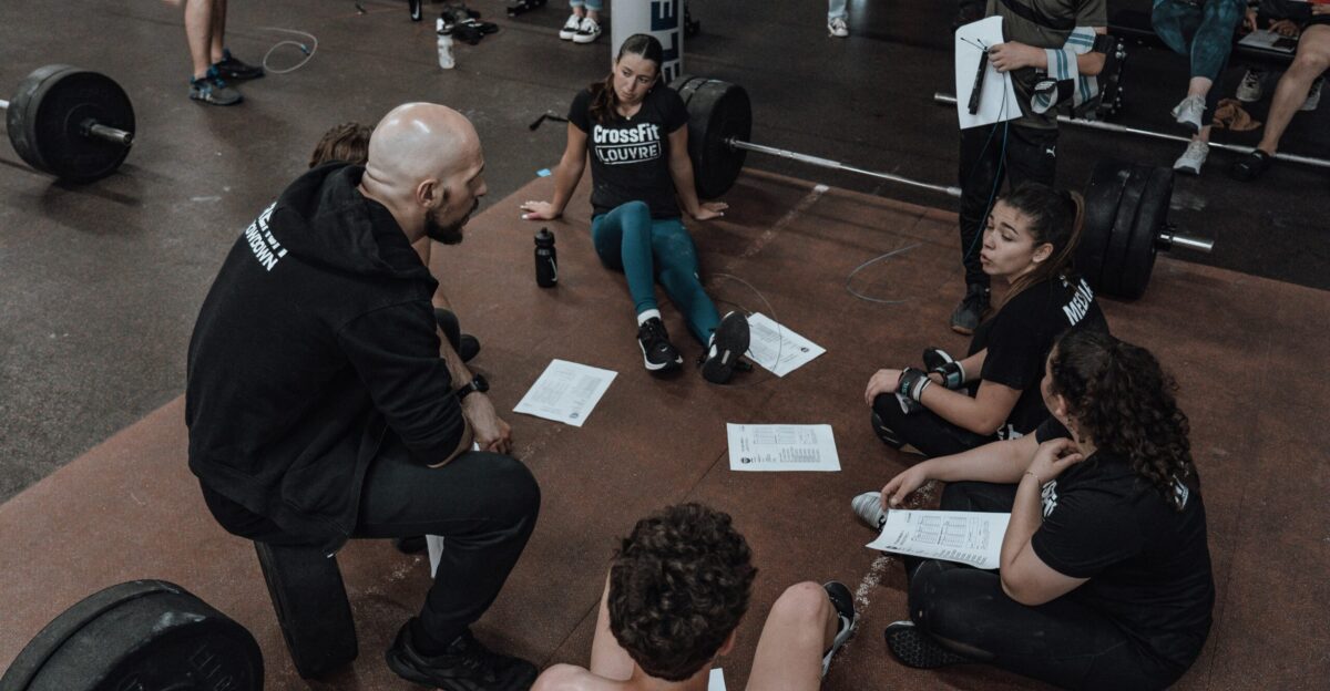 a group of people sitting on the ground in a gym