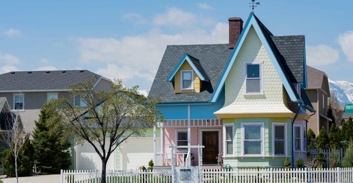 a multicolored house with a white picket fence