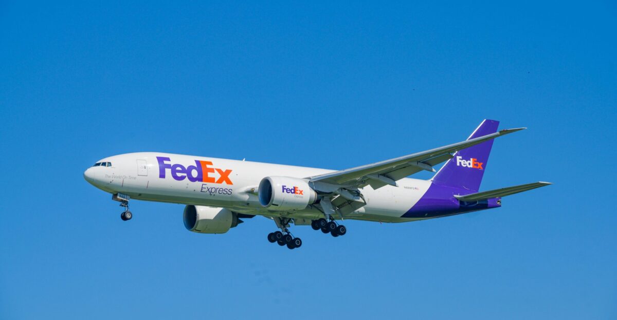 A fedex airplane flying in a clear blue sky