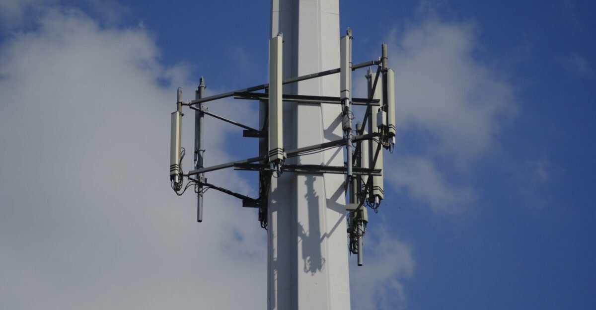 A cellular tower antenna reaches towards the sky