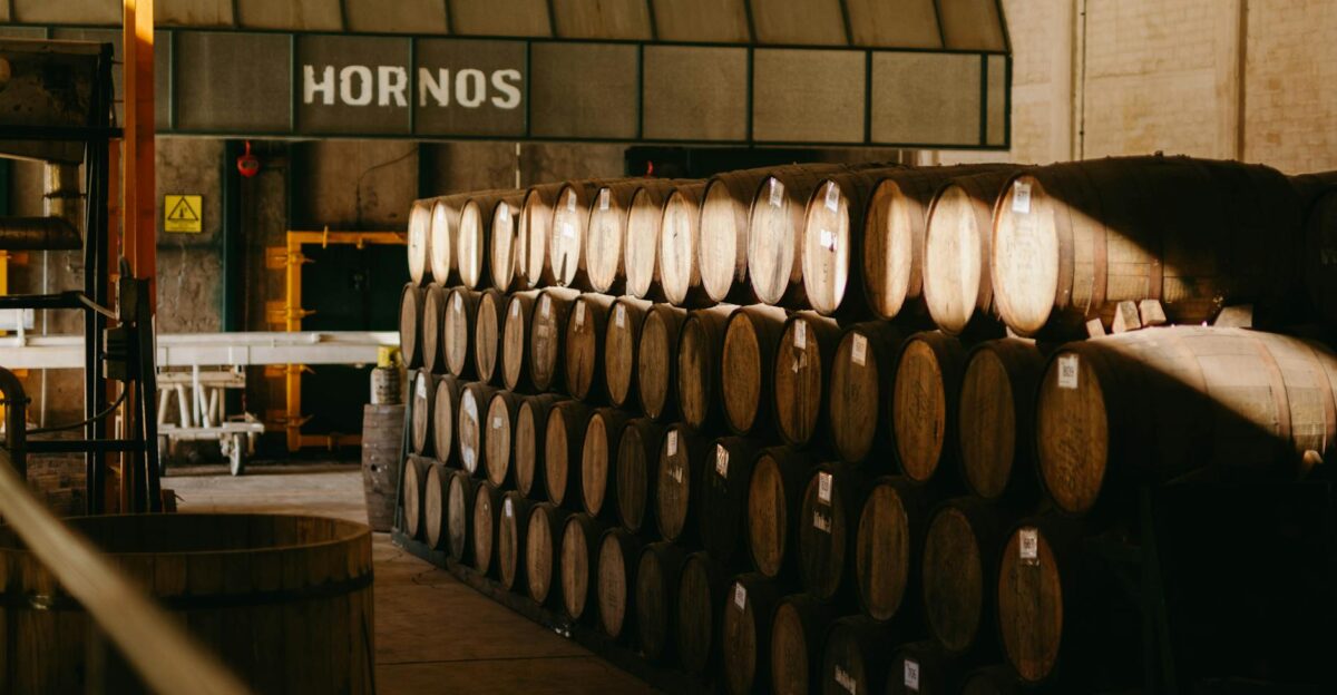 Wooden barrels aging tequila in a traditional Mexican distillery hall