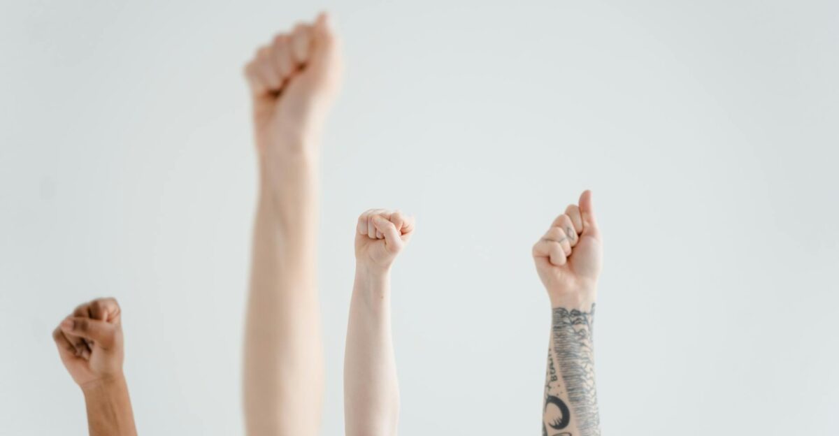 Hands raised in solidarity symbolizing unity and protest against a plain background